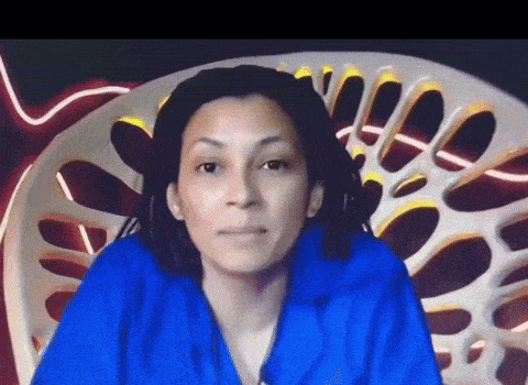 a woman wearing a blue shirt is sitting in front of a chair with holes in it