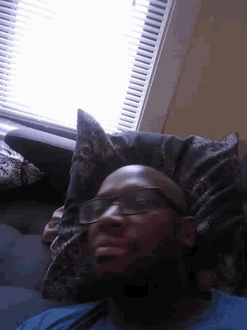 a man with glasses is laying on a pillow