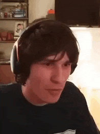 a man wearing headphones is making a funny face while sitting in front of a computer .