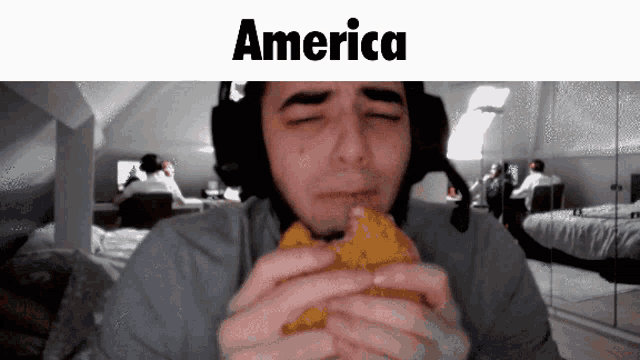 a man wearing headphones is eating a hamburger with the word america on the bottom
