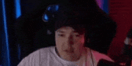 a man is wearing a hat and headphones while sitting in a chair .