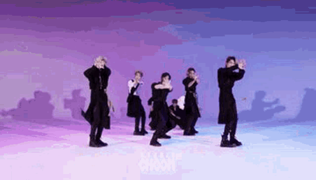 a group of men are dancing on a stage in front of a purple and blue background .