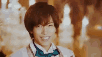 a young man wearing a bow tie and a white jacket is smiling .