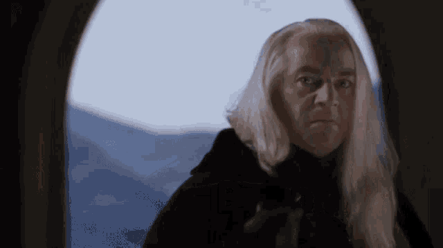 a man with long white hair is looking through a window .