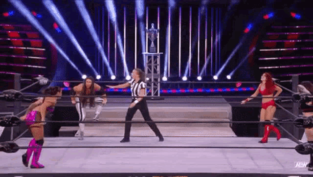 a referee is standing in the middle of a wrestling ring with a trophy in the background .