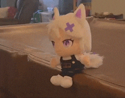 a white stuffed animal with a purple cross on its head sits on a table