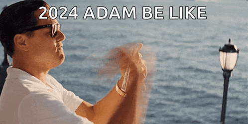 a man taking a picture of the ocean with the words 2024 adam be like above him