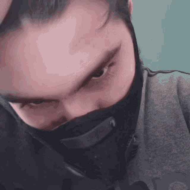 a man with a beard is wearing a black mask around his neck .