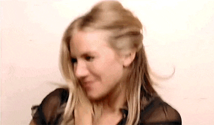a woman with long blonde hair is smiling and holding her hair in a half up half down hairstyle .