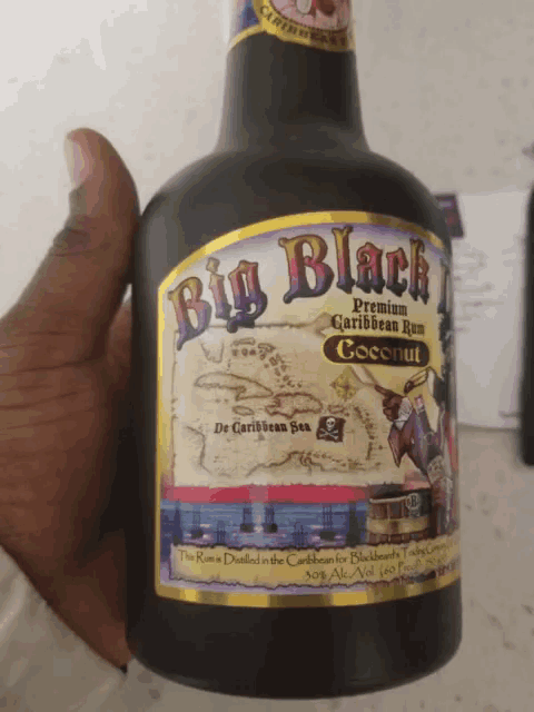 a person is holding a bottle of big black premium caribbean rum