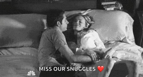 a man and a woman are laying on a bed hugging and kissing .