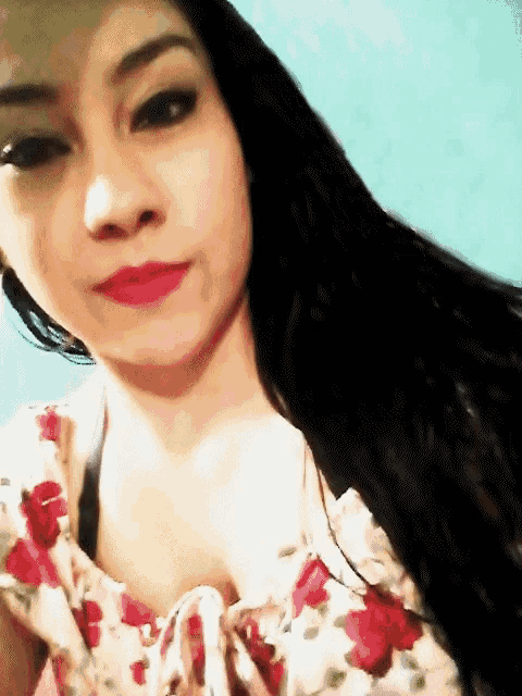 a woman with long black hair wearing a floral top