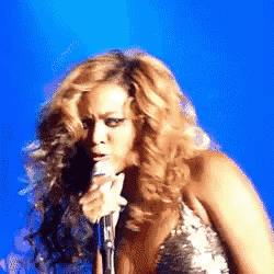 a woman singing into a microphone on a stage