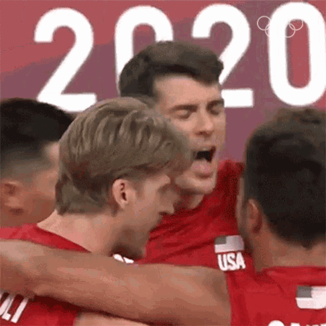 a group of men hugging each other in front of a sign that says 2020 .