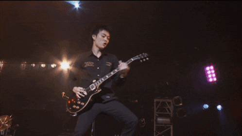a man playing a guitar on a stage with the letter d visible in the corner