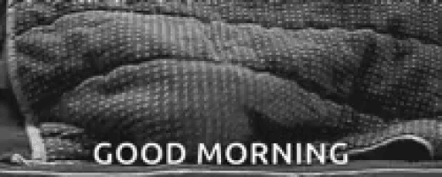 a black and white photo of a person laying on a bed with the words `` good morning '' above them .