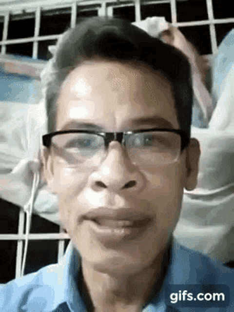 a man wearing glasses and a blue shirt is looking at the camera .