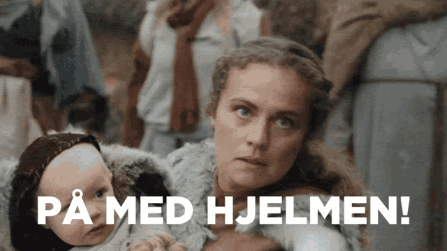 a woman holding a baby in her arms with the words pa med hjelmen written below her