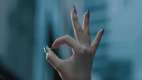 a woman with a ponytail and a necklace is making an ok sign