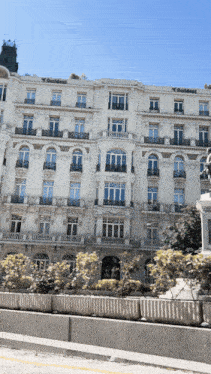 a large white building with balconies and a statue in front