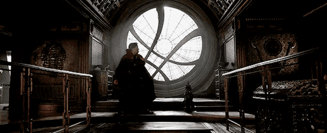 a man in a red cape is sitting in front of a large circular window .