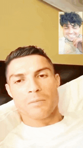 a man laying on a bed with a picture of another man on the wall behind him