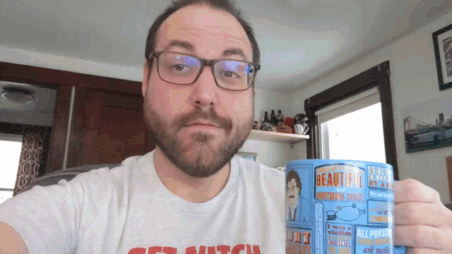 a man wearing glasses holds a mug that says beautiful on it