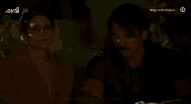 a man and a woman are sitting next to each other in a dark room with the number 13 on the bottom right corner