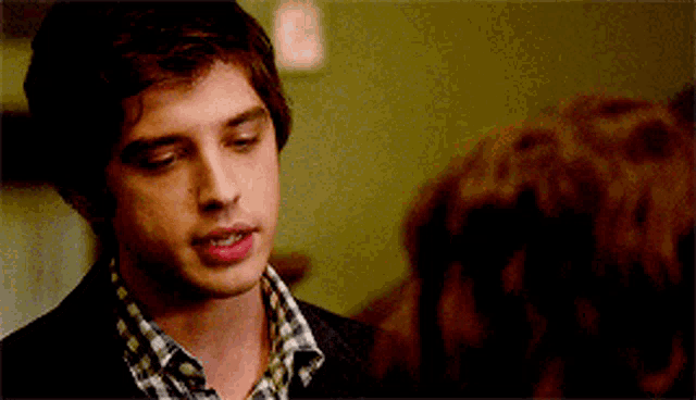 a man in a plaid shirt is looking at another man