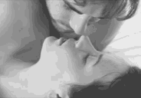 a black and white photo of a man kissing a woman on the forehead .