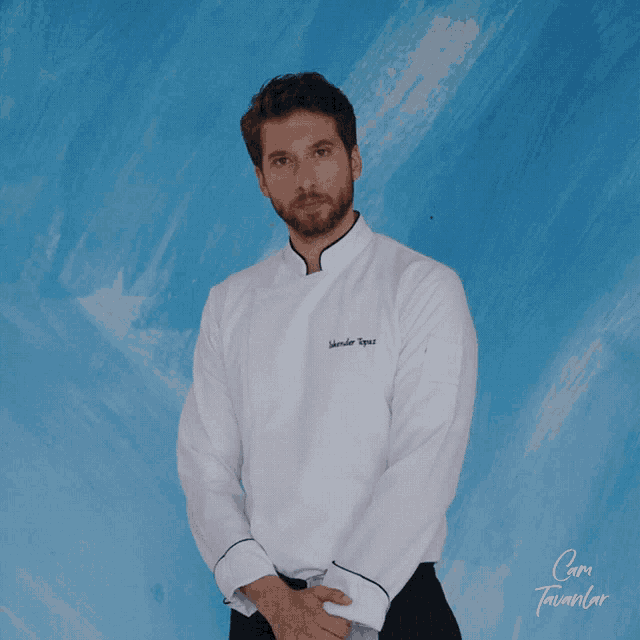 a man wearing a chef 's jacket with the name alexander tapas embroidered on the front