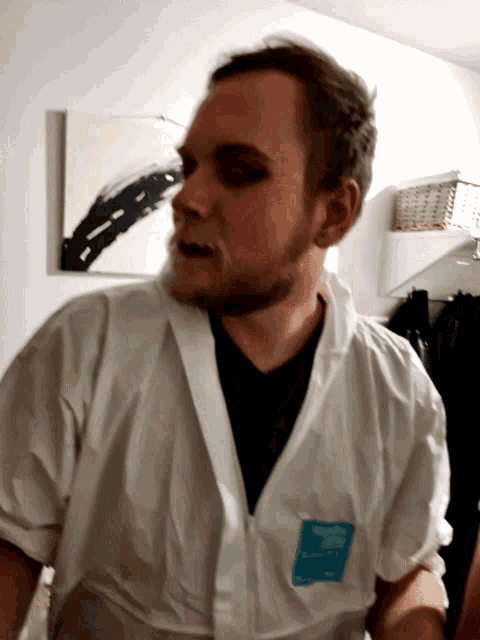 a man is wearing a white coverall with a blue label that says ' safety ' on it