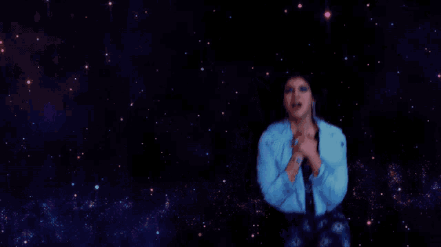 a woman in a blue jacket is standing in front of a galaxy