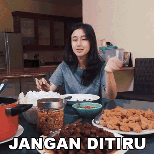 a woman sits at a table with plates of food and says jangan ditiru
