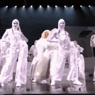 a group of people dressed in white dancing on a stage