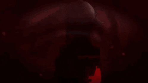 a close up of a person 's face in a dark room with a yellow background