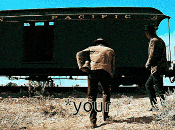 two men are standing in front of a train car that says pacific