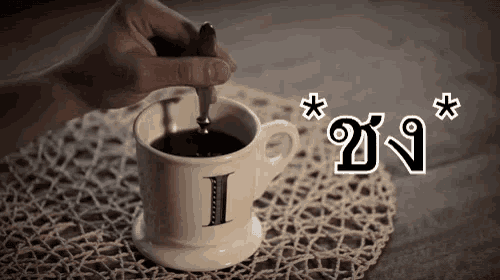 a person is stirring a cup of coffee with a spoon