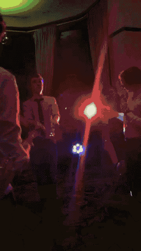 a group of people are dancing in a dark room with money falling from the ceiling