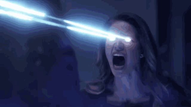 a woman is screaming and looking at a blue light coming from her eyes