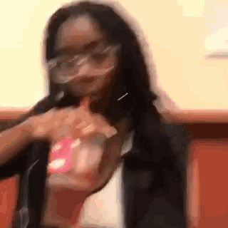 a woman wearing glasses is holding a bag of chips and giving a thumbs up .