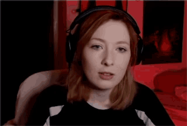 a woman wearing headphones is smiling in front of a red background .