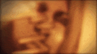 a blurry picture of a man and woman kissing in a room .