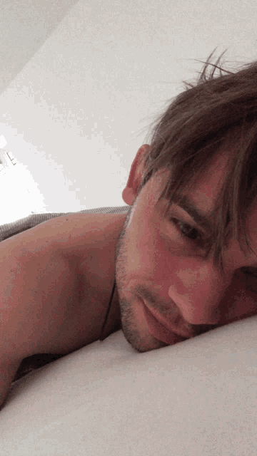 a man with a beard is laying on a bed looking at the camera