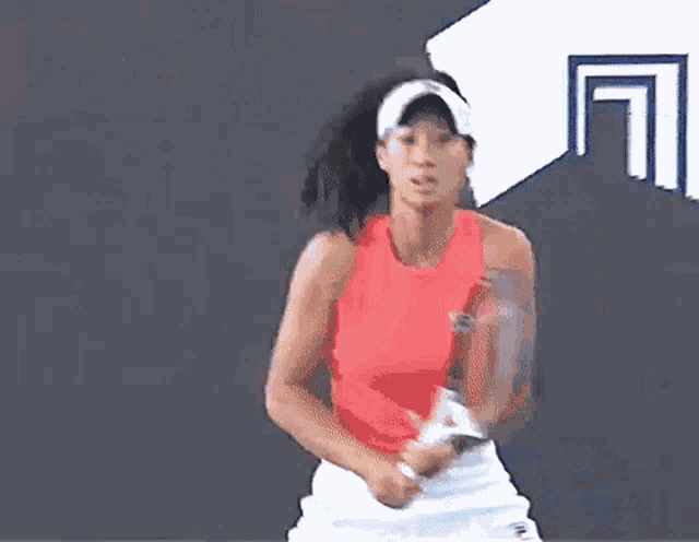 a woman in a red tank top is playing tennis