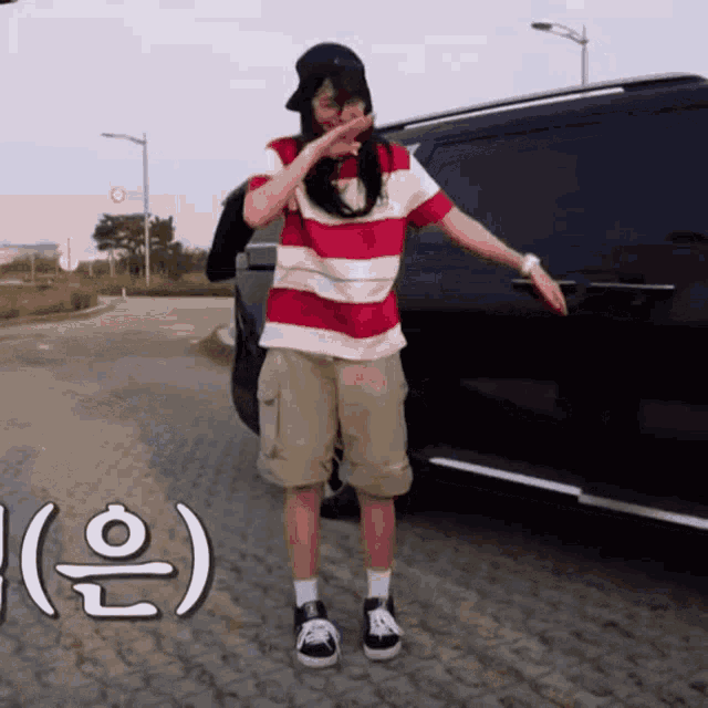a person wearing a striped shirt and shorts is standing in front of a black van