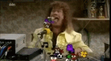 a man is singing into a microphone with a bunch of toys around him