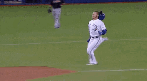 a baseball player wearing a blue jays jersey stands on a base