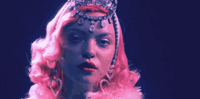 a woman with pink hair wearing a tiara and earrings