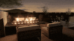 a patio area with a fireplace and chairs at night